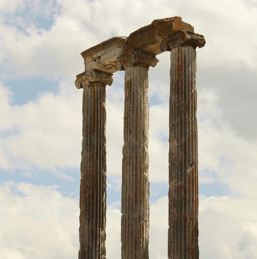 Majestic ancient Roman columns reaching toward the cloudy sky.